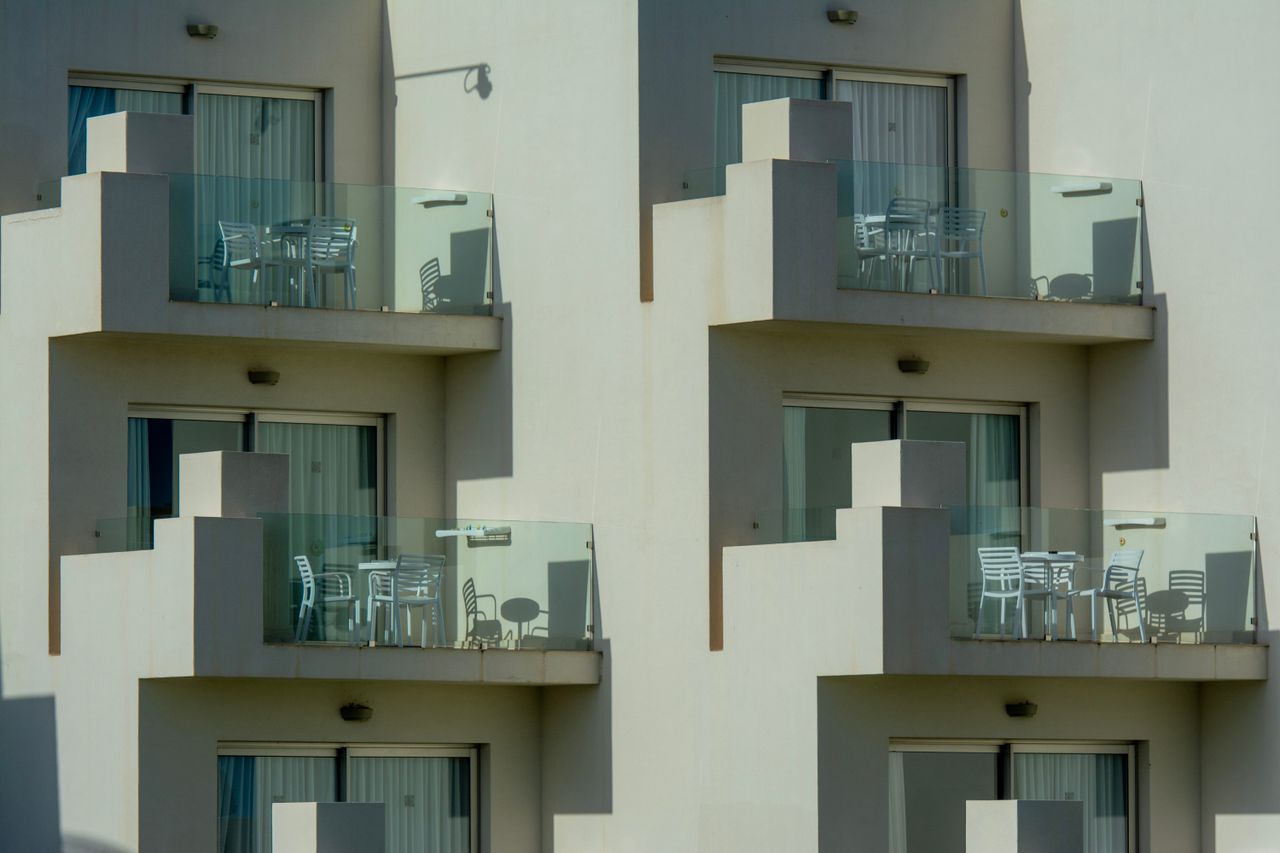 about-02 Architectural view of modern apartment balconies with sleek glass railings and outdoor furniture.