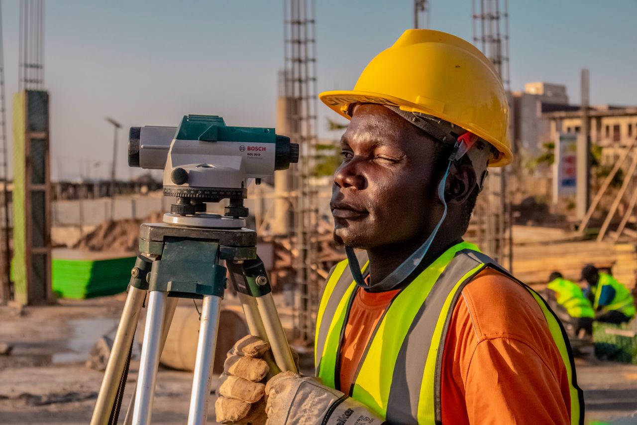 mission-02 A construction worker using a theodolite for land surveying at a building site.