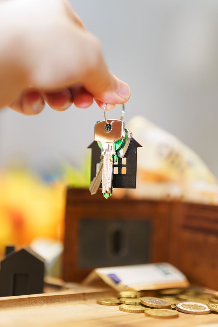 about-04 Hand holding house keys representing real estate investment with coins and wallet.